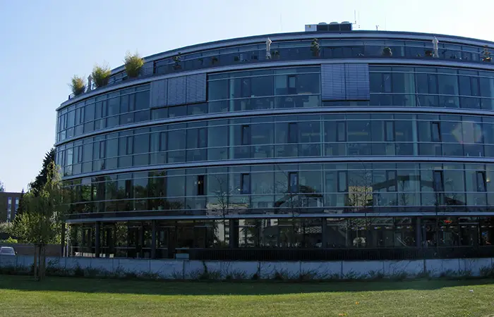 Rundes Bürogebäude mit Glasfassade und begrüntem Dach.
